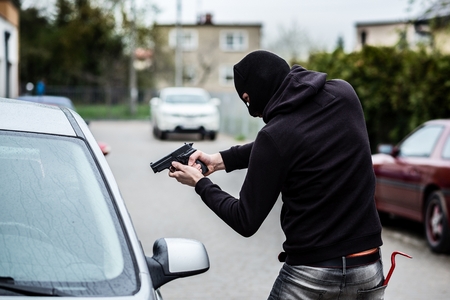 Terrorist or a car thief pointing a gun at the driver - car ownerの写真素材
