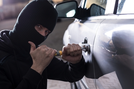 Car Thief tries to open car with screwdriver. Car thief, car theftの写真素材