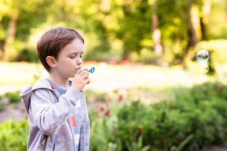 Children's Day.  Little boy blowing soap bubbles in the parkの写真素材