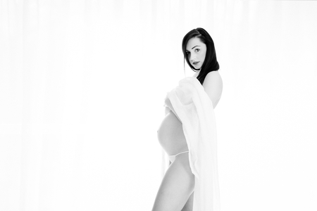 Beautiful brunette pregnant woman standing over white background - copy spaceの写真素材
