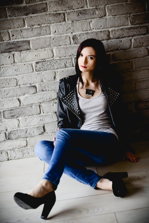 Sexy young brunette in leather jacket sittingの写真素材