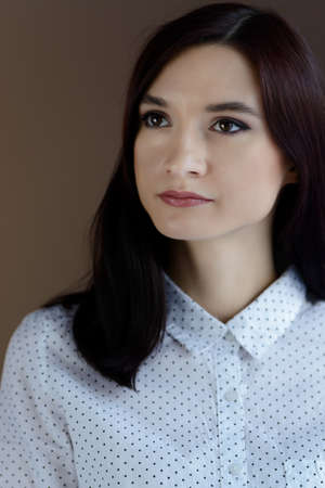 Portrait of young brunette woman in white shirtの写真素材
