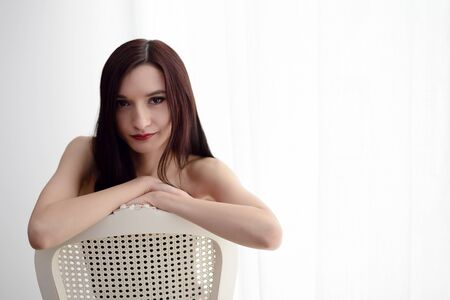 Sexy young brunette woman posing on chairの写真素材