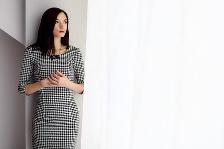 Formally dressed young brunette woman near windowの写真素材