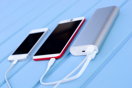 Powerbank charging two smartphones - outdoor, blue wooden backgroundの写真素材