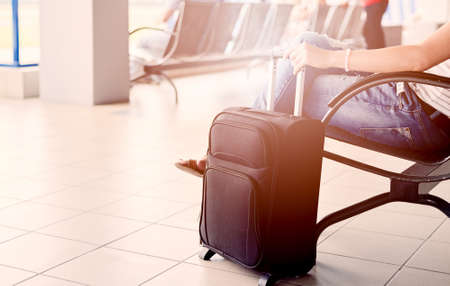 Woman waiting for her flight at airport and holding her luggageの写真素材