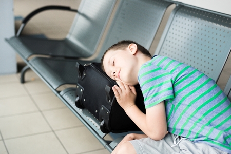 Tired child boy sleeping at the airport - canceled flightの写真素材