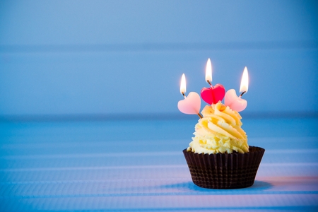 Birthday's cake - cupcake with a heart shaped candles for 3 - third birthday or valentine's day. Happy birthday !の写真素材
