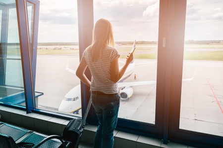 Woman books a flight with the smartphone at the airport.の写真素材