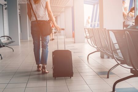Woman passes through the airport terminal with her luggageの写真素材