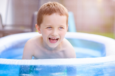 Happy little boy in inflatable garden poolの写真素材