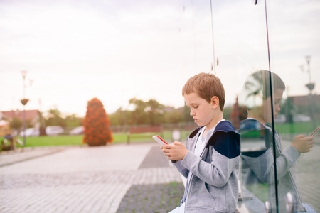 Little boy child playing mobile games on smartphone in the park.の写真素材