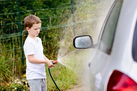 Little boy washing silver car in the garden. Summerの写真素材