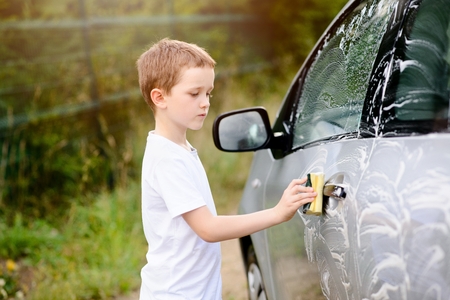 Little boy washing silver car in the garden. Summerの写真素材