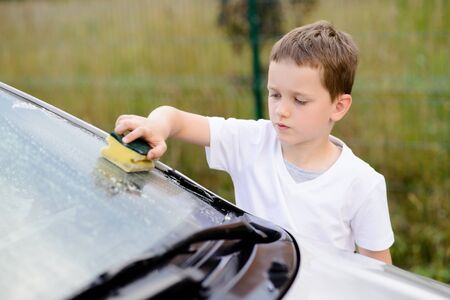 Little boy washing silver car in the garden. Summerの写真素材
