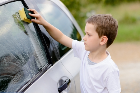 Little boy washing silver car in the garden. Summerの写真素材