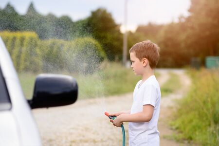 Little boy washing silver car in the garden. Summerの写真素材