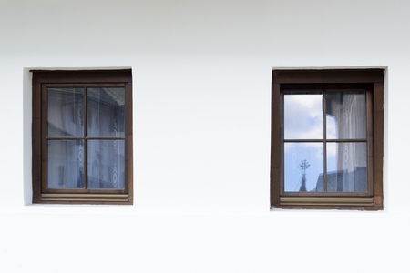 White wall with two old wooden stylized windowsの写真素材