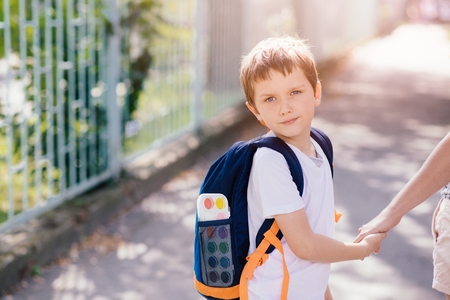 Little 7 years old boy going to school with his motherの写真素材