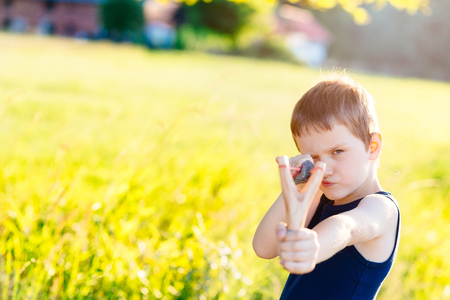 Little boy playing with slingshot at summer afternoon outdoorsの写真素材