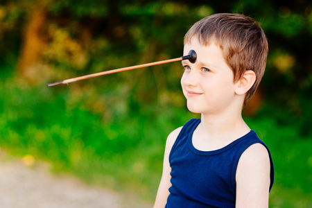 Little boy playing playing with bow and toy arrow at summer afternoon outdoorsの写真素材