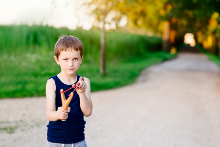 Little boy playing with slingshot at summer afternoon outdoorsの写真素材