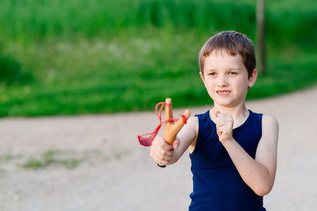 Little boy playing with slingshot at summer afternoon outdoorsの写真素材