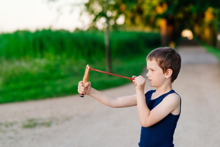Little boy playing with slingshot at summer afternoon outdoorsの写真素材