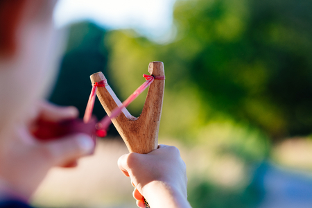 Little boy playing with slingshot at summer afternoon outdoorsの写真素材