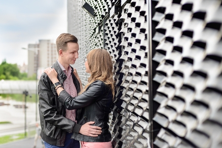 Young couple in love hugging outdoors. Engagement session. Dressed in black leather jackets. Girl wears glassesの写真素材
