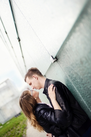 Young couple kissing. Engagement session. Dressed in black leather jackets. Girl wears glassesの写真素材