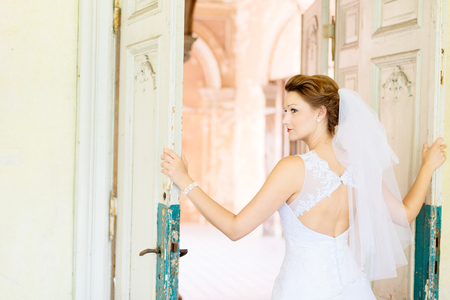 Young beautiful bride in white dress near old door . Wedding day. Wedding sessionの写真素材