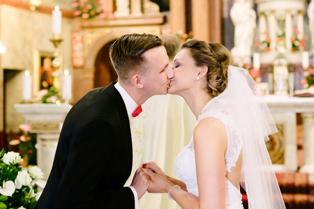 Wedding ceremony in catholic church - first kiss. Marriage vow. Wedding dayの写真素材
