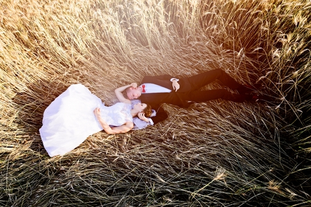 Newlyweds lying head to head on grain field. Above view. Wedding day. Wedding sessionの写真素材
