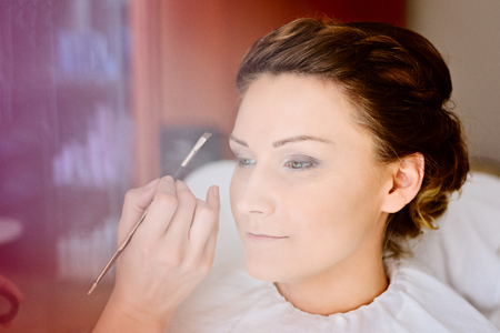 Makeup artist making a wedding makeup for bride. Wedding preparations. Bridal morning of a cute lady. Wedding day.の写真素材