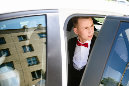 Groom getting out the wedding car. Wedding preparationsの写真素材