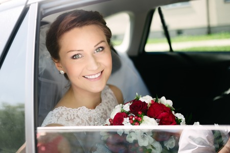 Beautiful young bride with bouquet in wedding car. Wedding preparations.の写真素材
