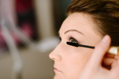 Makeup artist applying mascara on bride eyelashes. Wedding preparations. Bridal morning of a cute lady. Wedding day.の写真素材