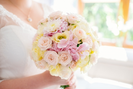Beautiful pastel wedding bouquet in hands of the bride. White and pink rosesの写真素材