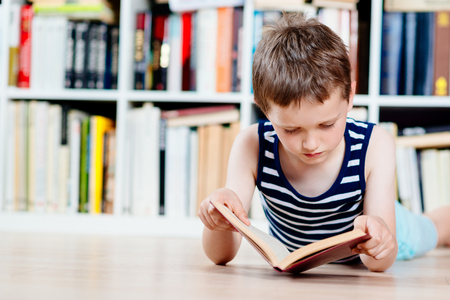Seven years old boy reading a book in library. Child readingの写真素材