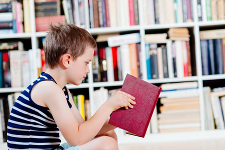 Seven years old boy reading a book in library. Child readingの写真素材
