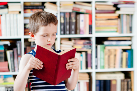 Seven years old boy reading a book in library. Child readingの写真素材