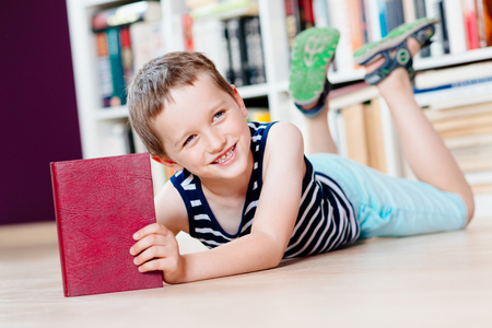 Seven years old boy reading a book in library. Child readingの写真素材