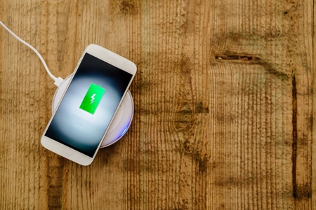 White smartphone charging on a charging pad. Wireless chargingの写真素材