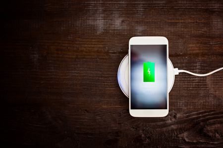 White smartphone charging on a charging pad. Wireless chargingの写真素材