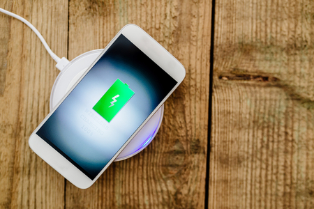 White smartphone charging on a charging pad. Wireless chargingの写真素材
