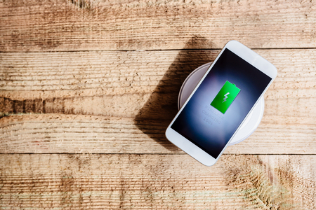 White smartphone charging on a charging pad. Wireless chargingの写真素材