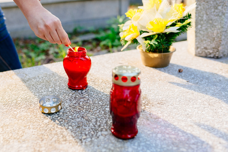 A woman lights a candle at the grave. Preparations for All Saints Day on November 1の写真素材