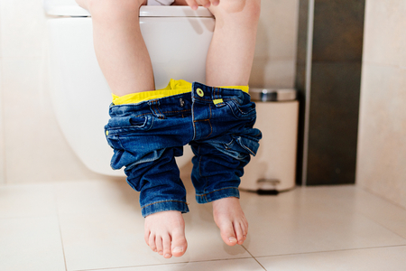 Little 7 years old boy on toilet. Low view on his legsの写真素材