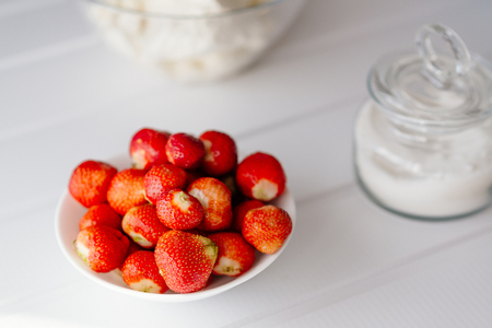 A bowl full of fresh red strawberries on white wooden backgroundの写真素材